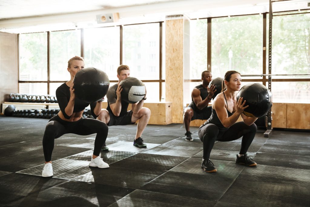 Exercise class of people squatting with medicine balls