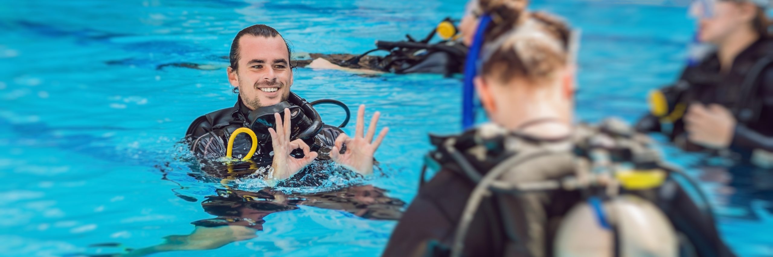 Diving instructor and students. Instructor teaches students to dive. BANNER, long format
