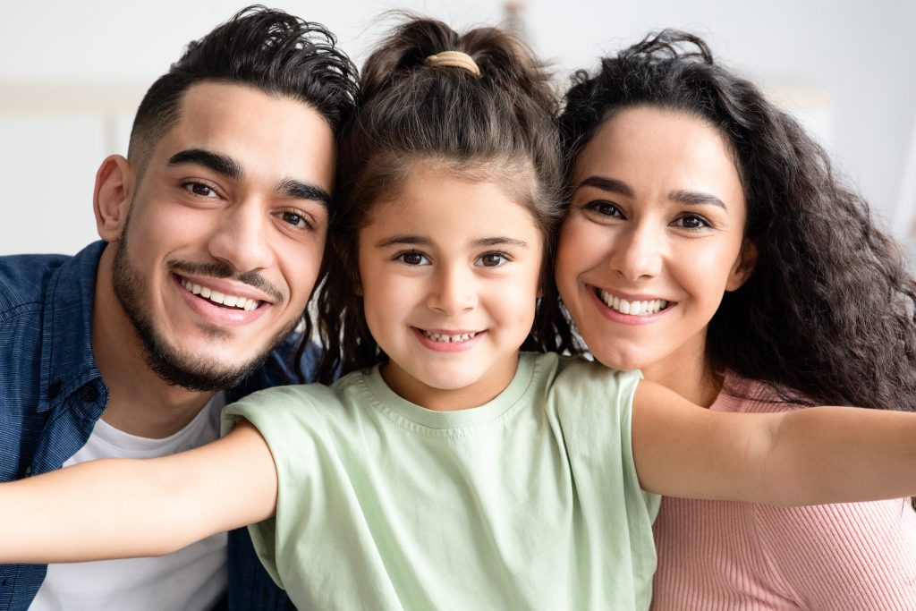 Young Family Portrait. Cute Little Girl Taking Selfie Photo With Her Arab Parents At Home, Happy Mom, Dad And Daughter Having Fun Together, Looking And Smiling At Camera, Closeup Shot