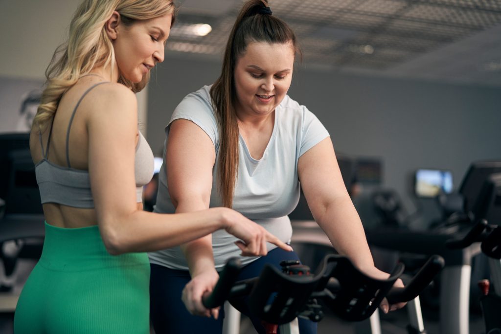 A personal trainer showing the client how to use bike