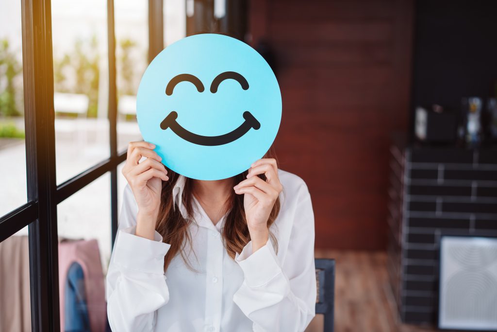 Asian woman holding blue happy smile face on paper cut