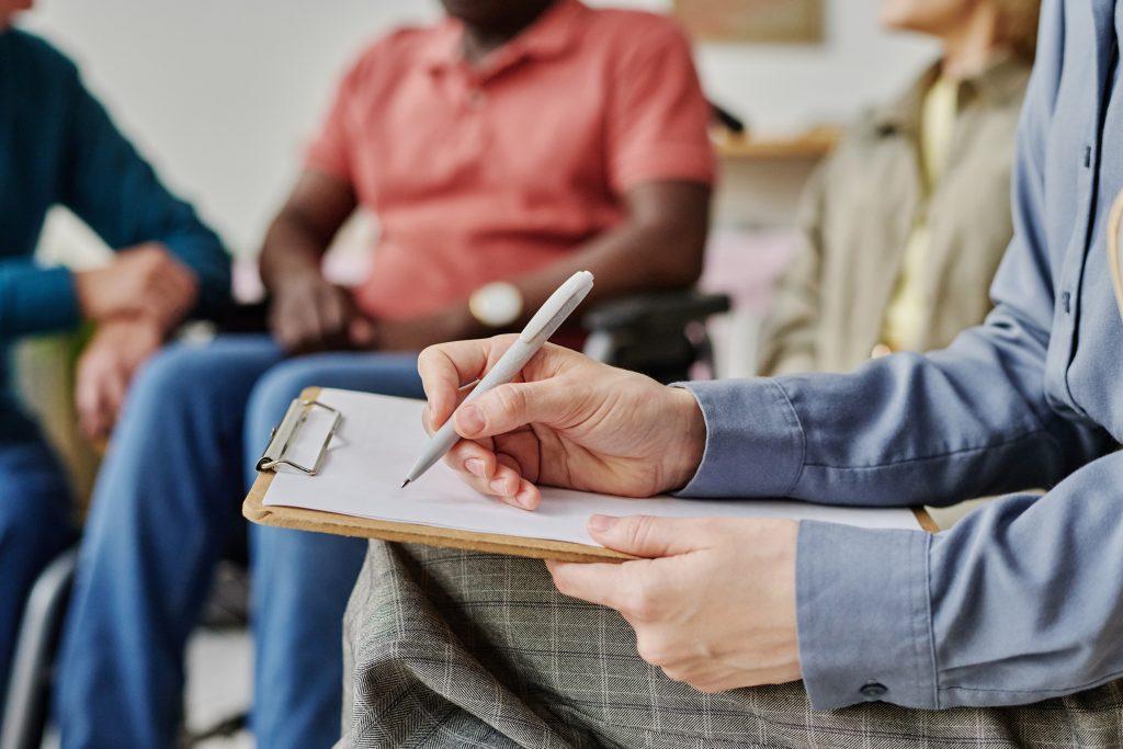Close-up of psychologist making notes in document while working with people at session