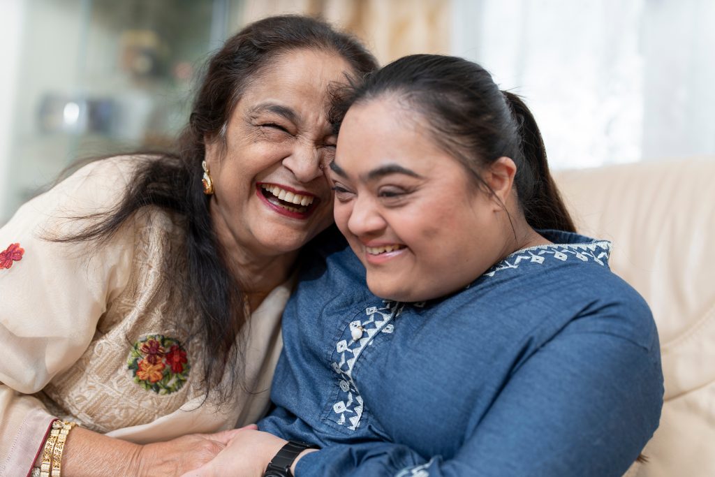 Woman laughing with down syndrome granddaughter in living room