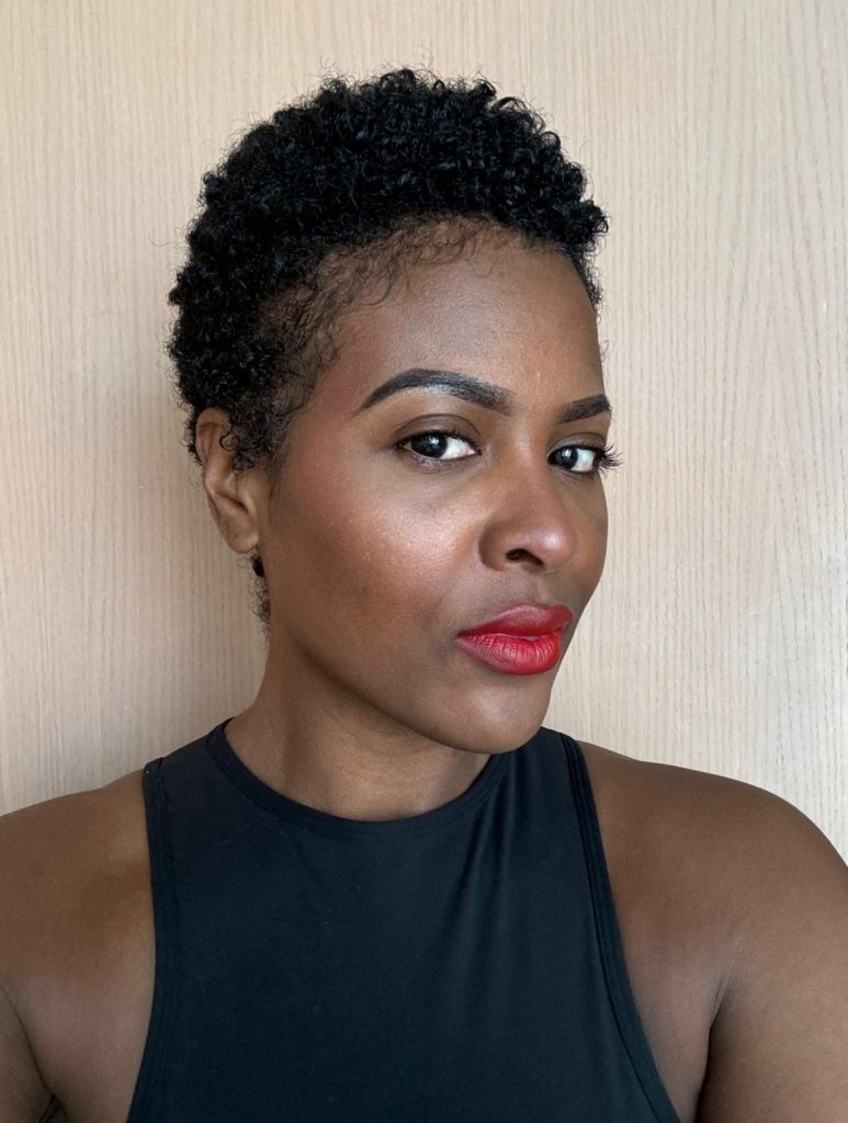 Black female with sleeveless black top with red lipstick and short hair