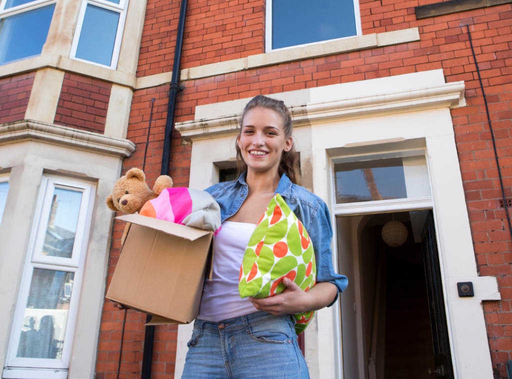 White young adults holding boxes and cushion moving into a property