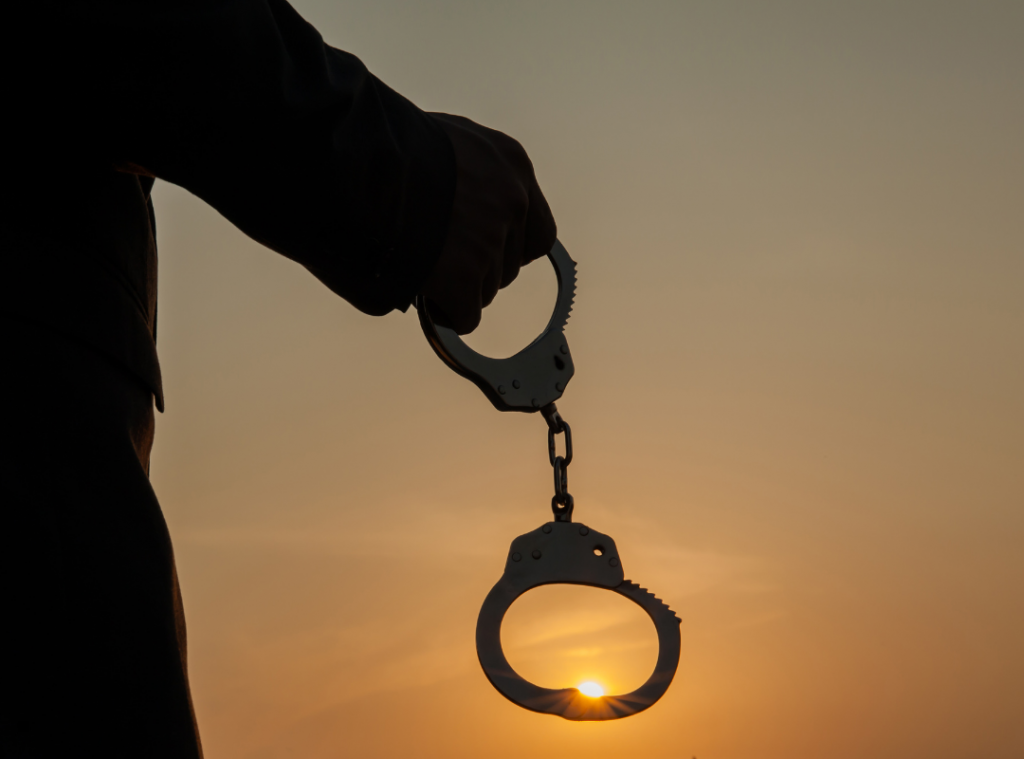 Man holding handcuffs in the sunset