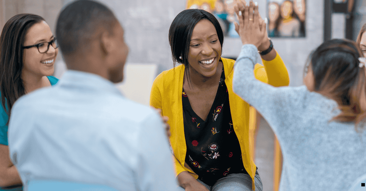 Black woman in a group setting high fiving a white person