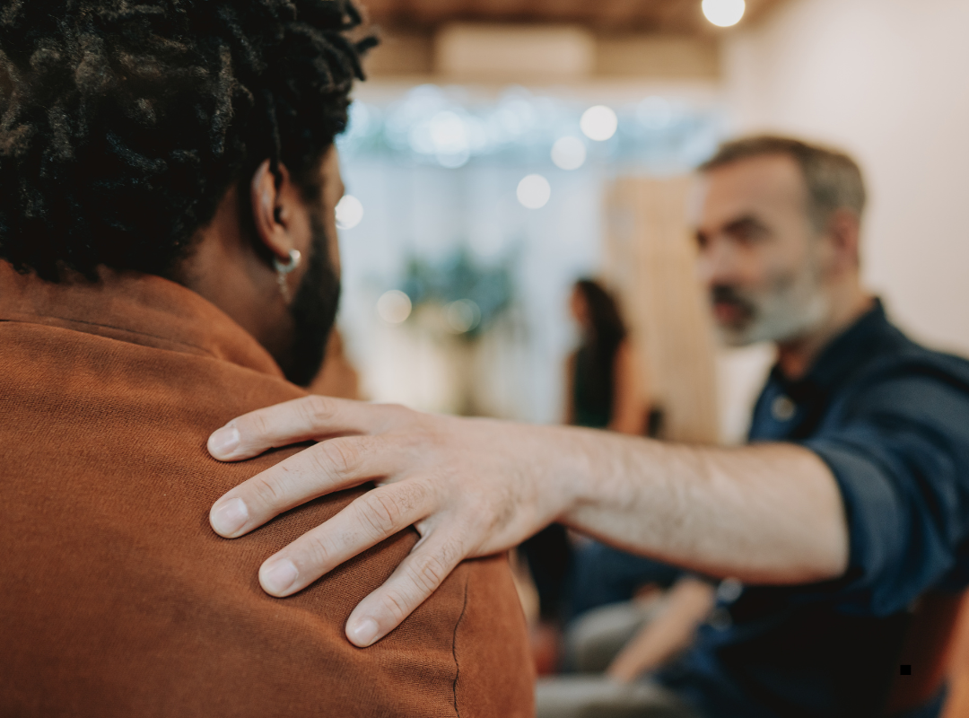 White support worker comforting a black man