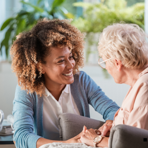 Black support worker supporting a white elderly woman