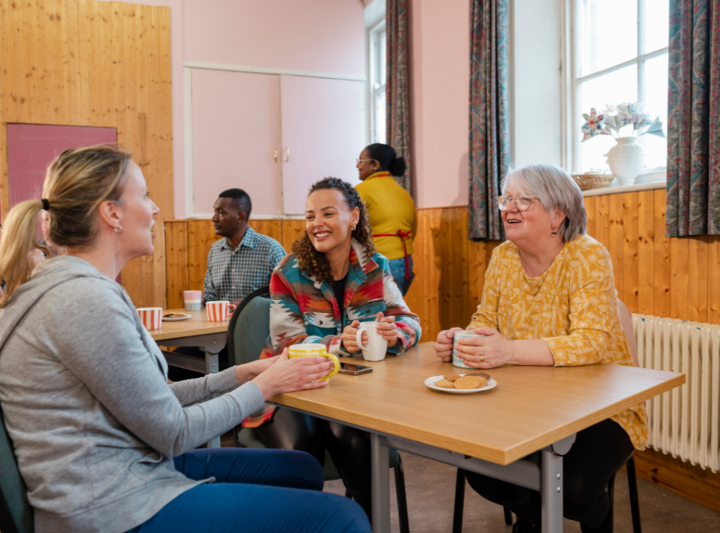 Community centre filled with community members sharing hot drinks and biscuits