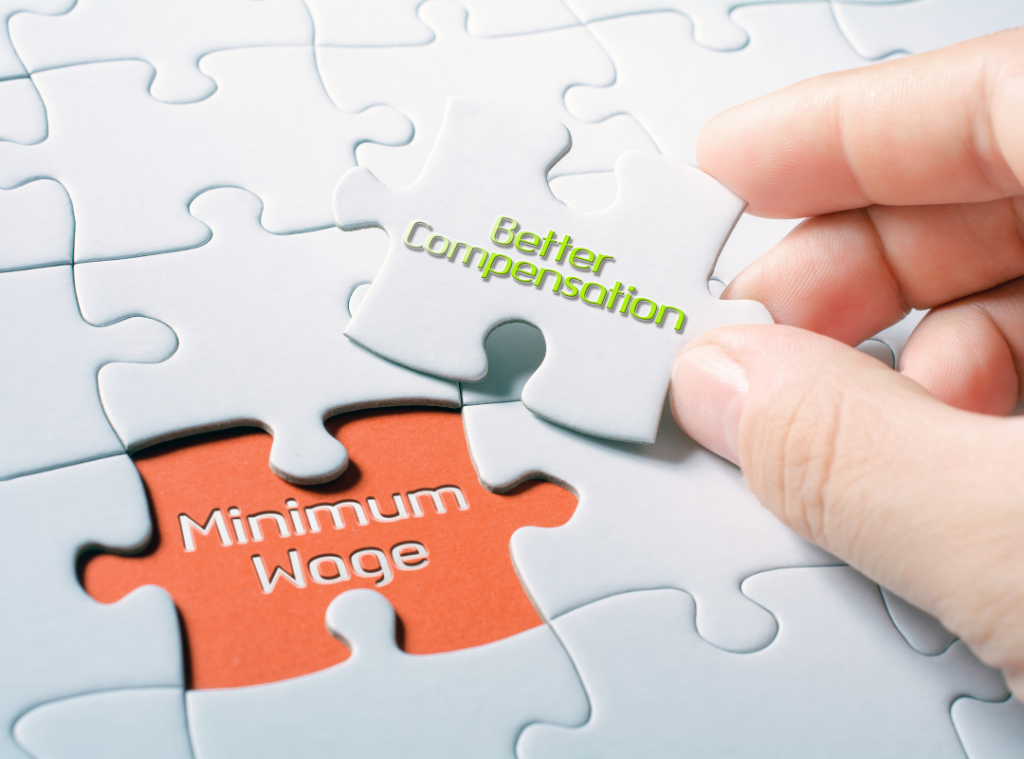 Minimum wage and better compensation puzzle piece being held by a white male