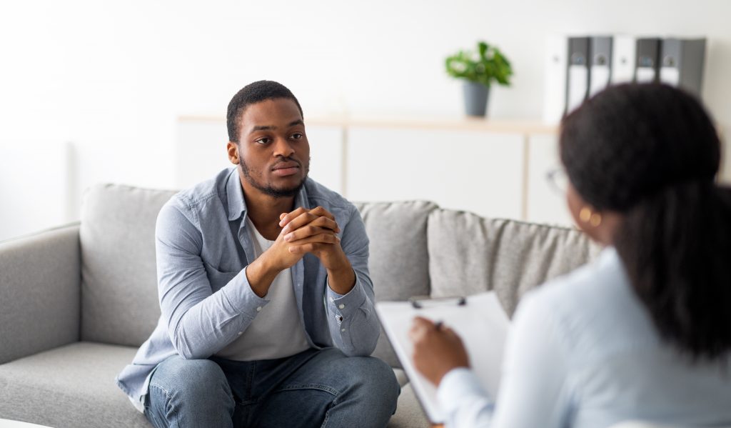 Psychological help service. Depressed male patient having psychotherapy session with counselor at mental health clinic